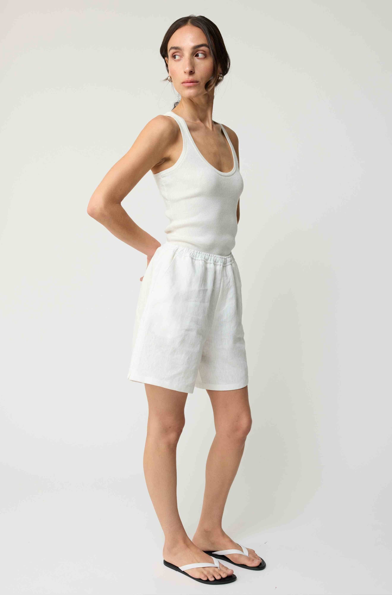 Woman wearing white linen shorts and a white tank top