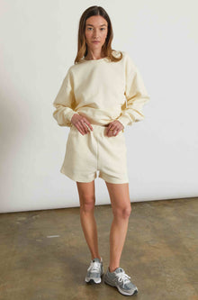Woman wearing a yellow sweatshirt and matching sweatshorts