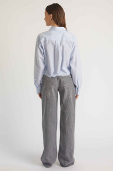 Person wearing a light blue shirt and gray pants on a white background