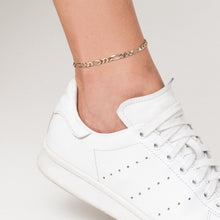 Model. Close up of foot with white sneaker and chain anklet