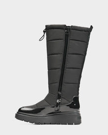 The Rudsak CLAUDE - L223506 Black women's tall quilted winter boot features a shiny patent toe and heel, quilted upper, side zipper, ridged sole, and top drawstring. This waterproof boot is stylish, warm, and comfortable.