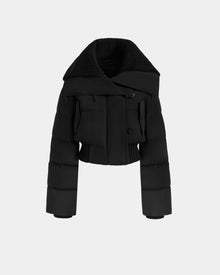 The Rudsak YVETTE - L125557 Black is a women’s cropped down jacket with RDS-certified filling, an oversized collar, wide sleeves, and front buttons. Shown on a plain light gray background, its modern structure creates a sleek statement.