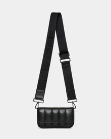 The CHARLI X - 8324009 Black by Rudsak is a small black quilted leather crossbody bag with a wide adjustable strap embossed with the brand name, sleek metal hardware, and a minimalist rectangular design.