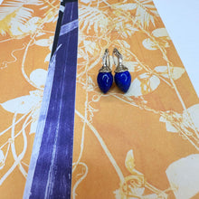Lapis drop earrings with yellow gold and diamond ripple bales, on a leaf patterned background.
