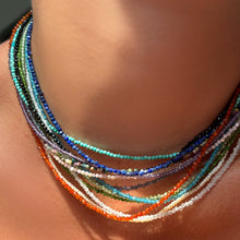 Slim gemstone necklaces layered on the neck.