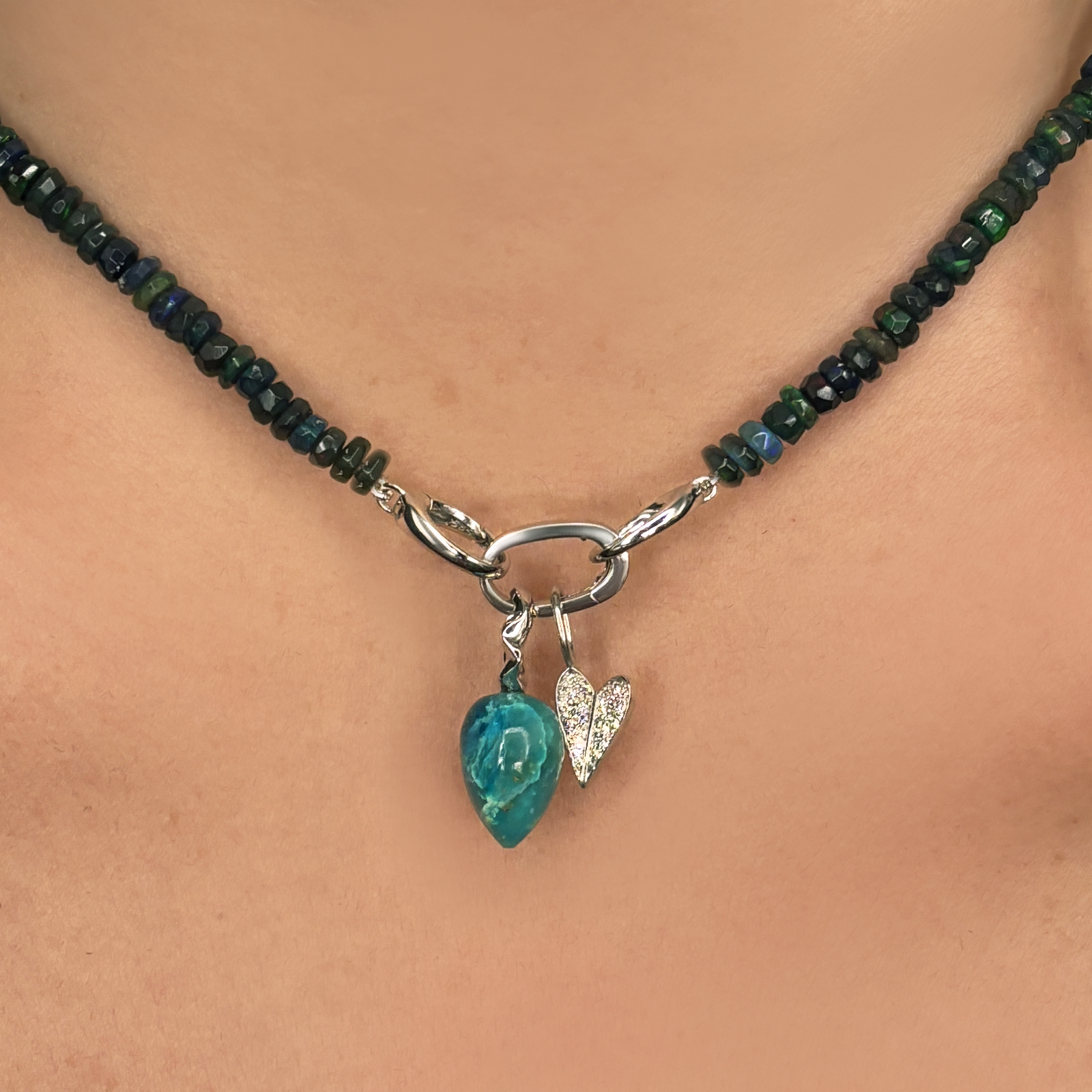 Small White Gold Folded Heart Charm with Full Pavé with a white gold oval charm lock and gemstone drop charm styled on an opal necklace. 